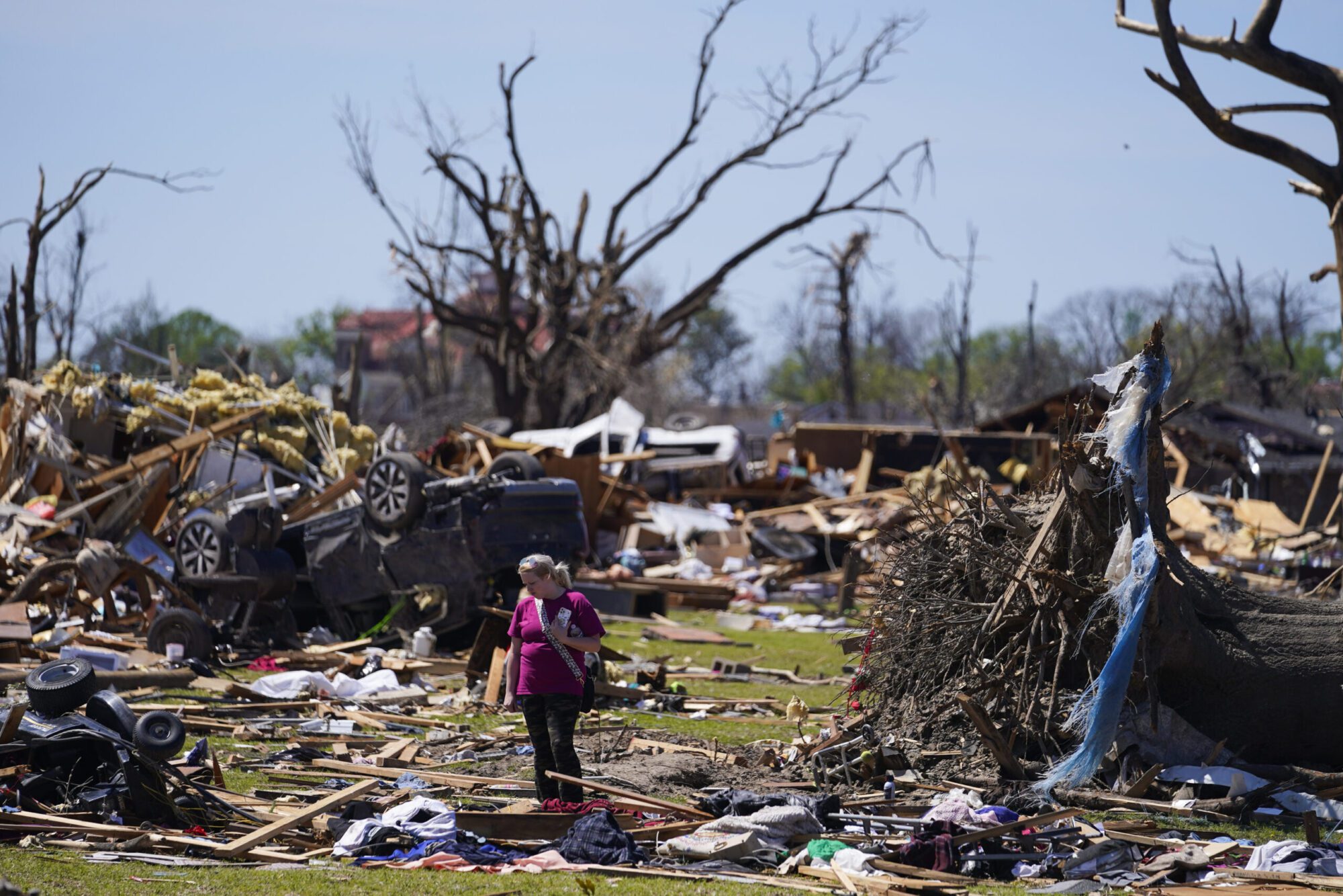A woman walks near an uprooted tree, a flipped vehicle and debris from homes damaged by a tornado, Monday, March 27, 2023, in Rolling Fork, Miss. (AP Photo/Julio Cortez - Copyright 2023 The Associated Press. All rights reserved.)
